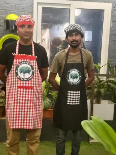 two men wearing aprons standing next to each other at Homestay by the Tea Garden Dibrugarh in Dibrugarh