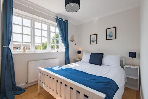 a bedroom with a large bed with blue curtains at St George's - stylish family home in Sandwich in Kent