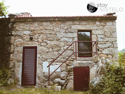 an old stone building with a red door and a staircase at Casa da Carreirinha in Arcos de Valdevez