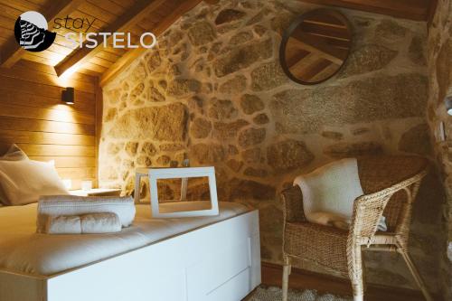 a room with a stone wall with a bench and a mirror at Casa da Carreirinha in Arcos de Valdevez