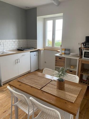 a kitchen with a wooden table and white chairs at Studio dans ferme en rénovation in Touille
