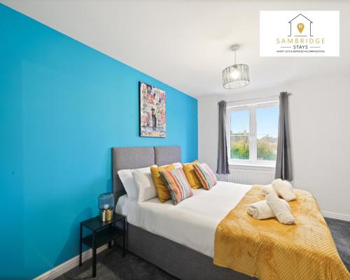 um quarto com uma cama com uma parede azul em Beautiful 2 Bedroom Seviced Apt in Aylesbury By Sambridge Stays Short Lets & Serviced Accommodation em Aylesbury