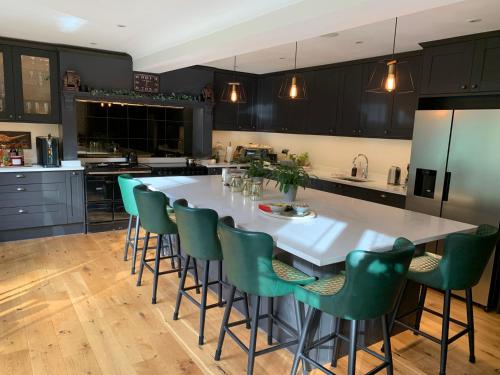 una cocina con una gran mesa blanca y sillas verdes en Stunning Surrey Hills Country House set in half an acre en Hindhead