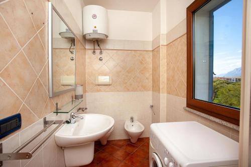 een badkamer met een wastafel, een toilet en een raam bij Le Residenze Blu Sardinia in La Caletta