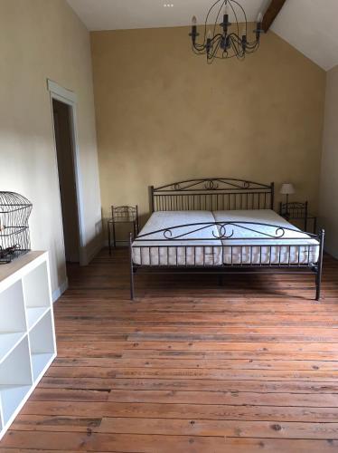 une chambre avec un lit et un parquet dans l'établissement Au p’tit bonheur d’Augé Maison, à Augé