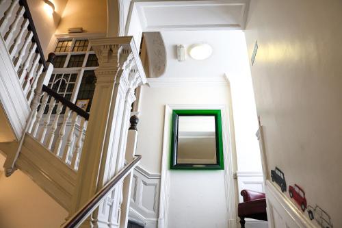 a stairway with a green framed mirror on the wall at Astor Hyde Park Hostel in London