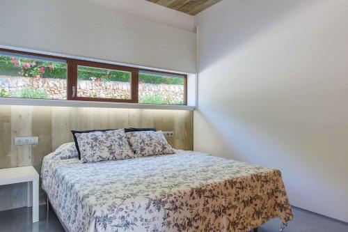 サン・リュイスにあるVilla Ullastres Ses Alzinesのベッドと2つの窓がある寝室