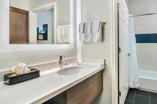 Staybridge Suites Tyler University Area, an IHG Hotel في تايلر: حمام أبيض مع حوض ومرآة
