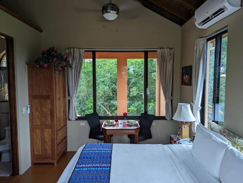 a bedroom with a bed and a table and windows at Villa Cayo in San Ignacio