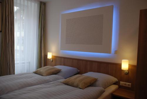 ブレッテンにあるHotel Rest Innのベッド2台 壁に照明が付く部屋