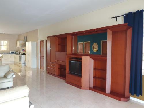 a large kitchen with wooden cabinets and a tv at Chander's Villa in Paramaribo