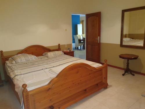 1 dormitorio con cama de madera y espejo en Chander's Villa, en Paramaribo