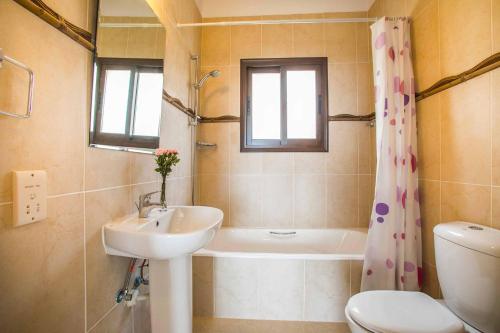 uma casa de banho com um lavatório, uma banheira e um WC. em Villa Blue Jadeite em Kissonerga