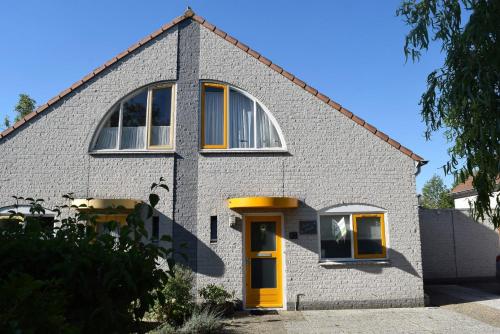 a white brick house with a yellow door at Kustverhuur, Vakantiepark Fort Soleil 43 in Breskens
