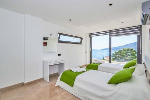 a white bedroom with two beds and a window at Villa Resital in Kalkan