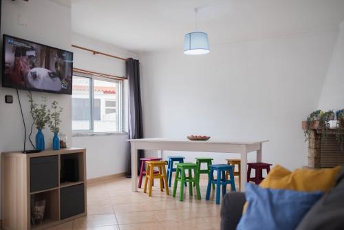 a living room with a table and colorful chairs at Baleal Surf Emotions in Baleal