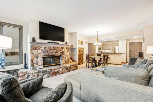 a living room with couches and a stone fireplace at Arrowhead Ski Condo in Edwards