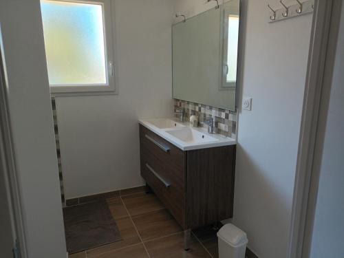 W łazience znajduje się umywalka i lustro. w obiekcie Maison proche Futuroscope w mieście Chasseneuil-du-Poitou