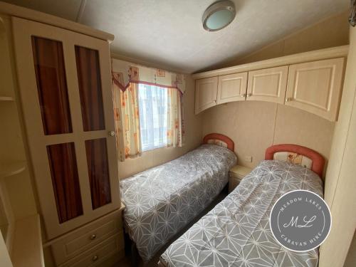 ein kleines Zimmer mit zwei Betten und einem Schrank in der Unterkunft Coral Beach - Row 73 Van 2, central heating, WiFi, bed linen - Meadow Lakes Caravan & Lodge Hire in Ingoldmells