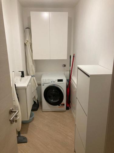 a small bathroom with a washing machine and a sink at Appartamento romantico con piscina in Cervo