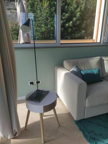 a living room with a couch and a lamp on a table at Appartamento romantico con piscina in Cervo