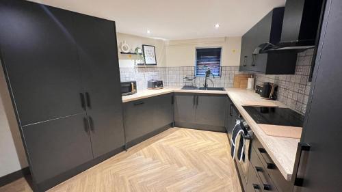 a kitchen with gray cabinets and a wooden floor at 6 Bed House that Sleeps up to 12, close to Elland Rd and City Centre in Beeston Hill