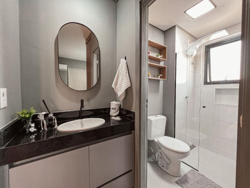a bathroom with a sink and a toilet and a mirror at Condomínio Residencial Unique Residence - São José do Rio Preto in Sao Jose do Rio Preto