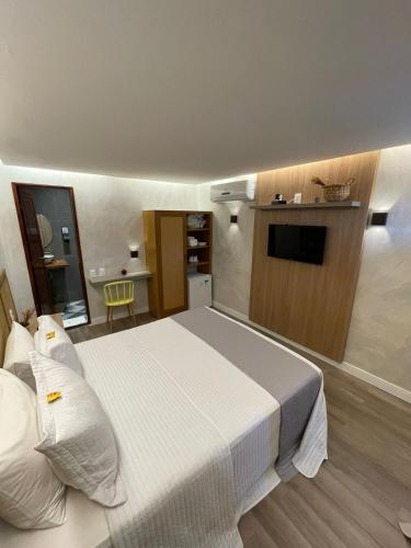 a bedroom with a white bed and a television at Pousada do Paiva in Flecheiras