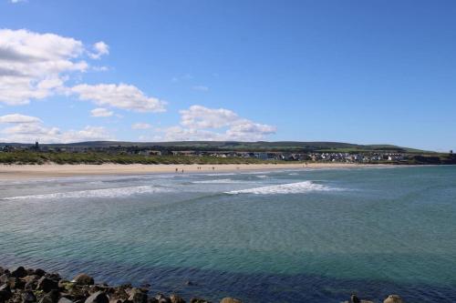 a beach with a group of people in the water at Sea View Studio in Castlerock