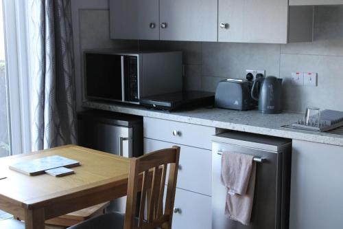 a kitchen with a wooden table and a microwave at Sea View Studio in Castlerock