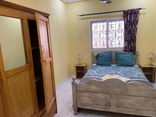 a bedroom with a bed with blue pillows and a window at The Compound in Bijilo