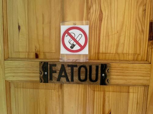 a sign on a wooden wall with a no smoking sign at The Compound in Bijilo