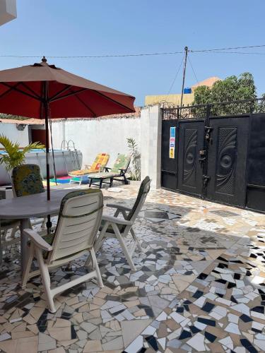 a patio with a table and chairs and an umbrella at The Compound in Bijilo