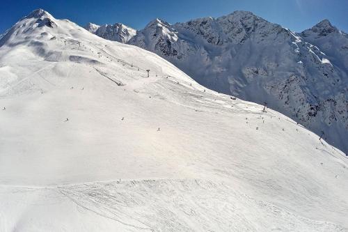 a snow covered mountain with people skiing down a snow covered slope at Ferienappartements Heinzle - Ihr Ferienresort in Sankt Jakob in Defereggen