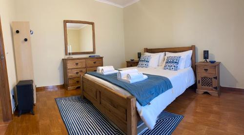 1 dormitorio con 1 cama grande y espejo en Alojamento CASA DA FIGUEIRA, en Ponta Delgada