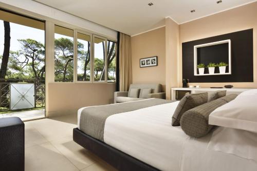 Riva Del Sole Resort & SPA في كاستيغليون ديلا بيسكايا: غرفة نوم بسرير ابيض كبير وتلفزيون