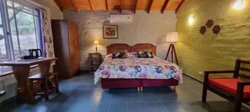a bedroom with a bed and a table and a chair at Hostal La Quebrada in Cortaderas