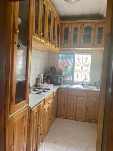 a kitchen with wooden cabinets and a sink and a window at The Compound in Bijilo
