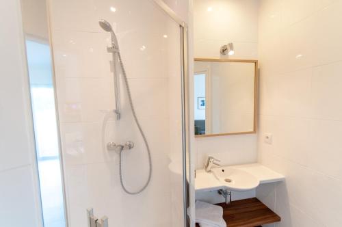 a white bathroom with a shower and a sink at Domaine équestre de la Chênaie in Saumur