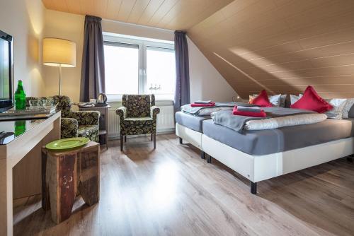 a hotel room with two beds and a desk at Hotel Villa Norderney in Neßmersiel