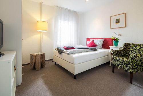 Un pequeño dormitorio con una cama y una silla. en Hotel Villa Norderney, en Nessmersiel