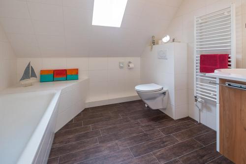 a white bathroom with a toilet and a sink at Hotel Villa Norderney in Neßmersiel