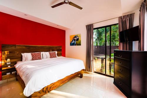 1 dormitorio con cama y pared roja en A Tamarindo Sunset, en Tamarindo
