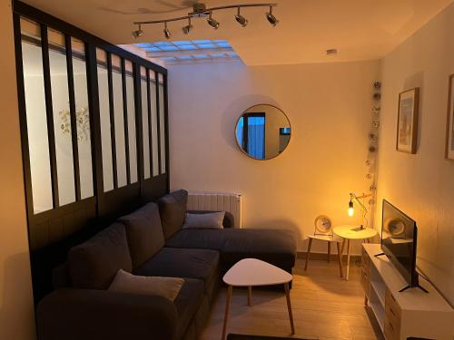 een woonkamer met een bank en een spiegel bij Logement cosy avec terrasse privée hypercentre in La Rochelle