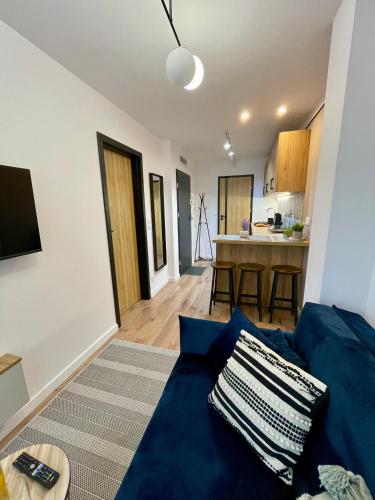 a living room with a blue couch and a kitchen at Apartament w sercu miasta in Radom