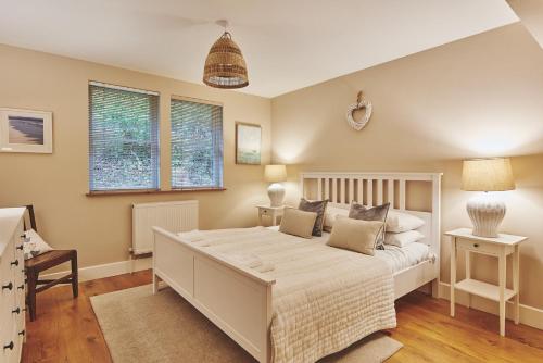 a bedroom with a white bed and two windows at Ty Seren in Oxwich