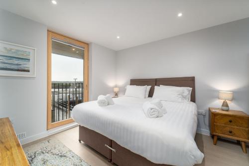 a bedroom with a large white bed and a window at Surfside in Hayle