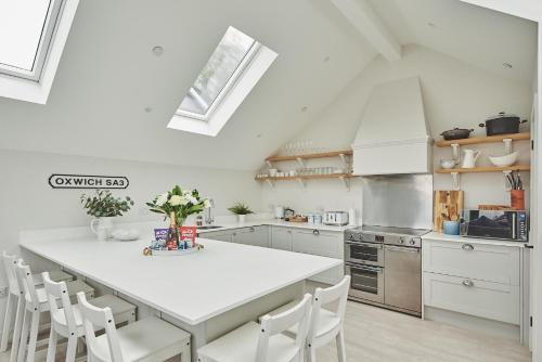 a white kitchen with a white table and chairs at Ty Megan in Oxwich