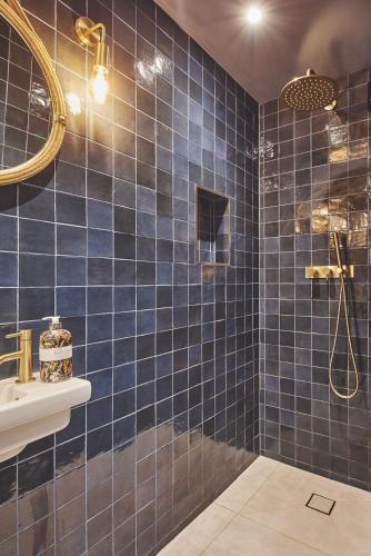 a blue tiled bathroom with a shower and a sink at Ty Alice in Oxwich