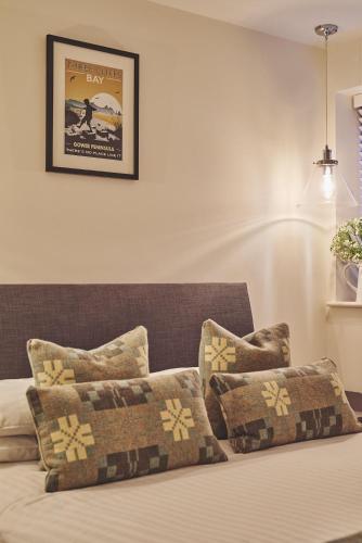 a bed with pillows and a picture on the wall at Ty Alice in Oxwich